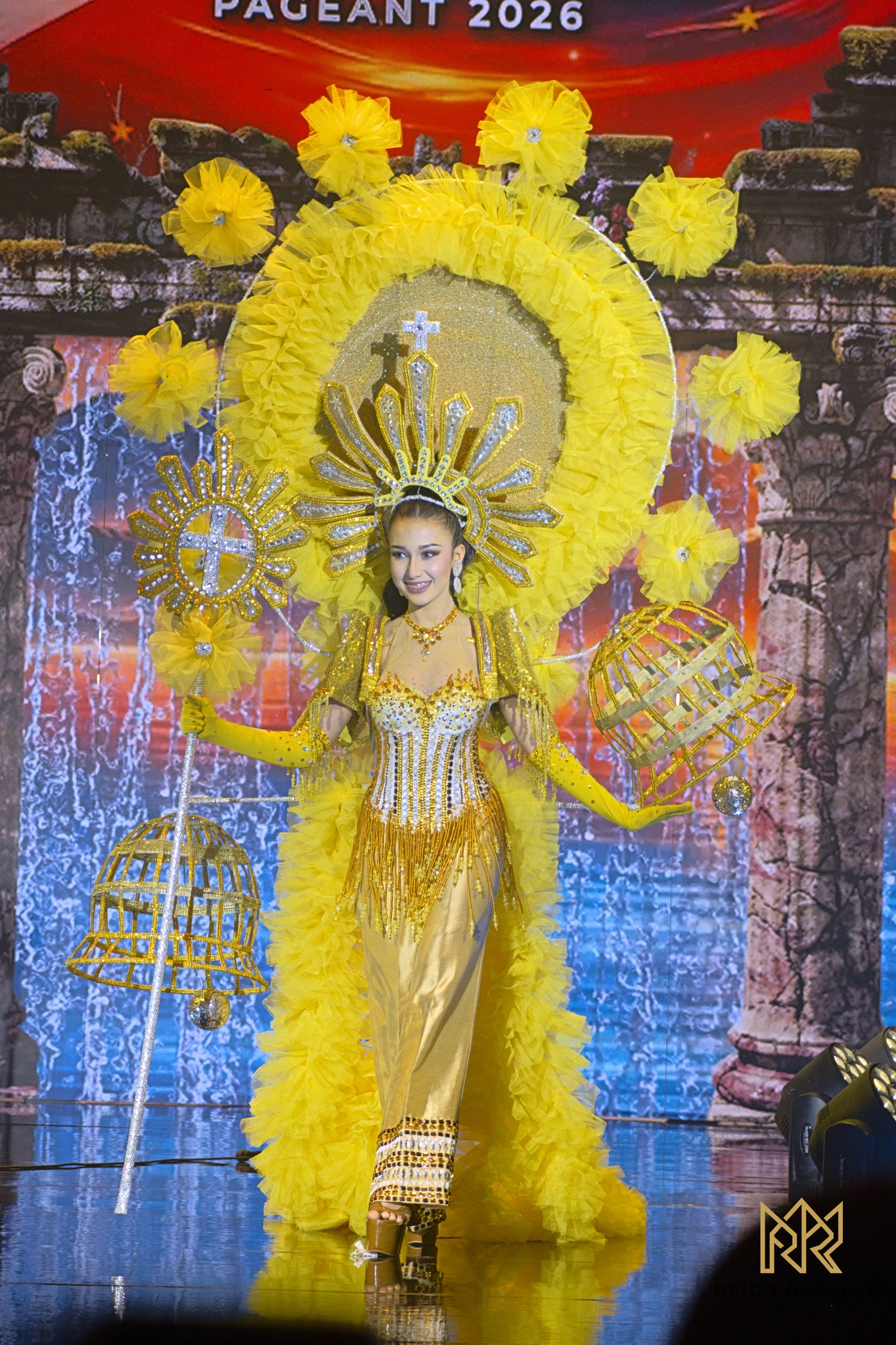 A candidate in a golden sunburst national costume.