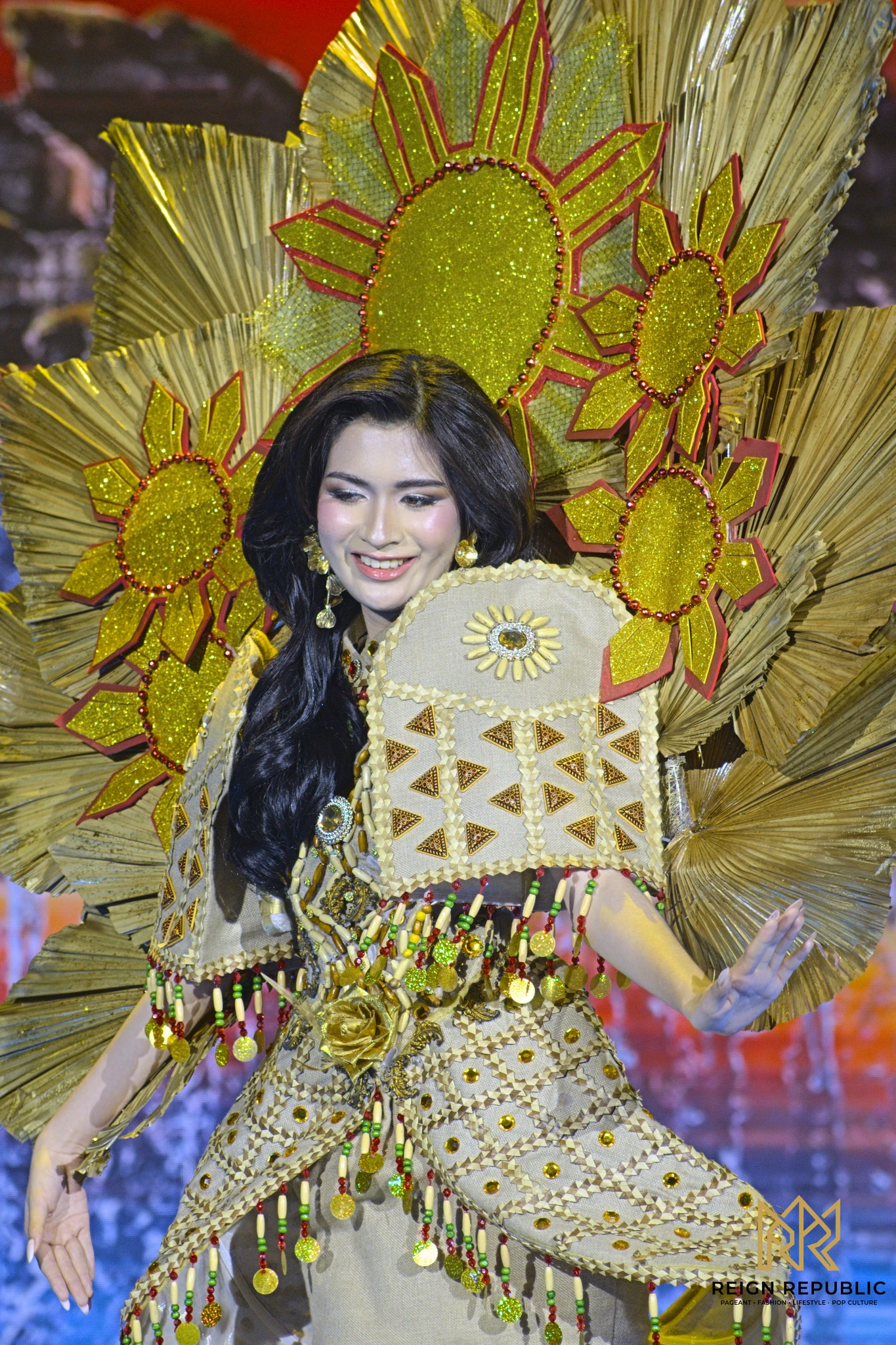 A candidate in a gold national costume with a sun headdress.