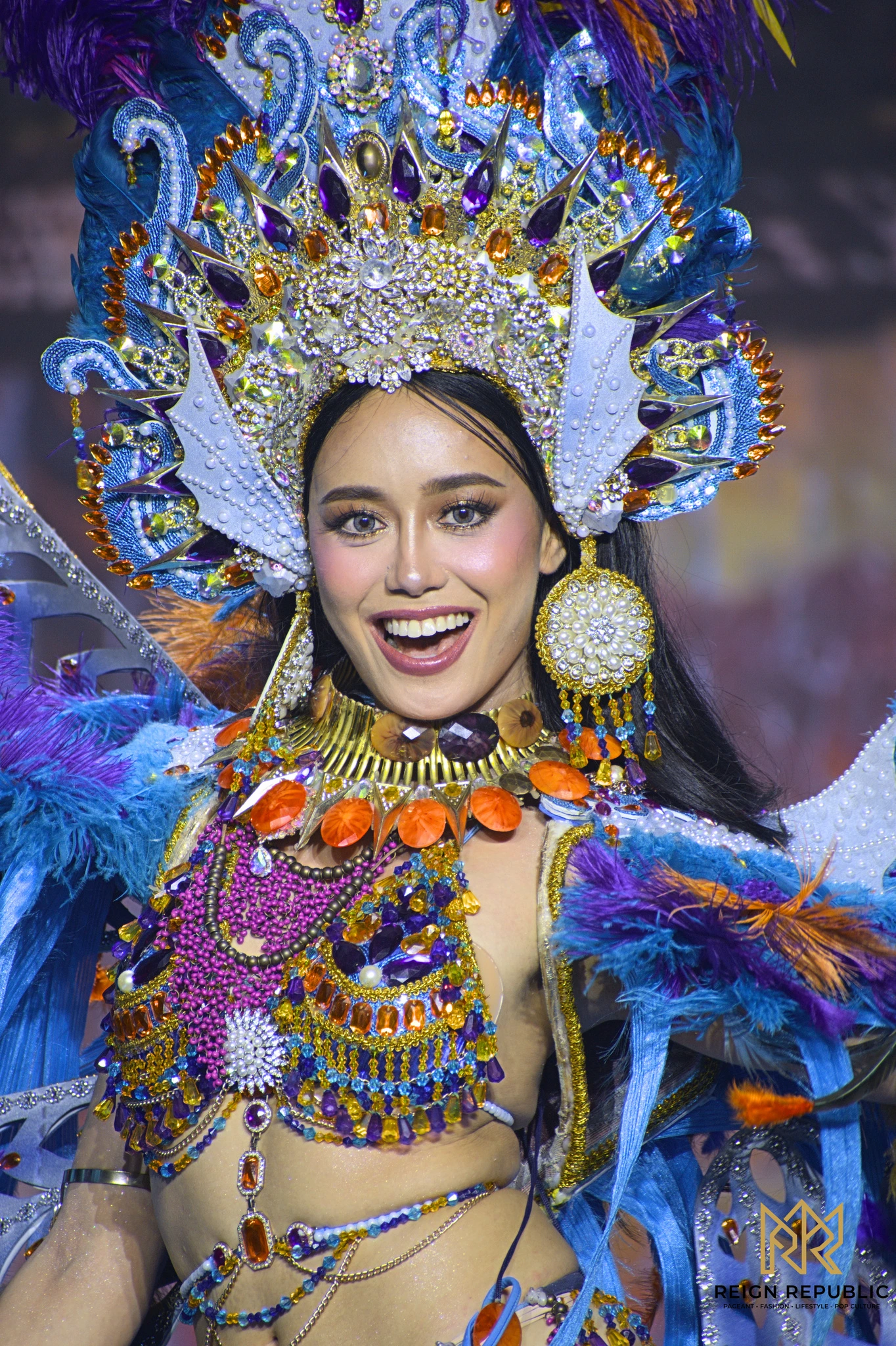 A candidate in a blue and gold national costume with a jeweled headdress.